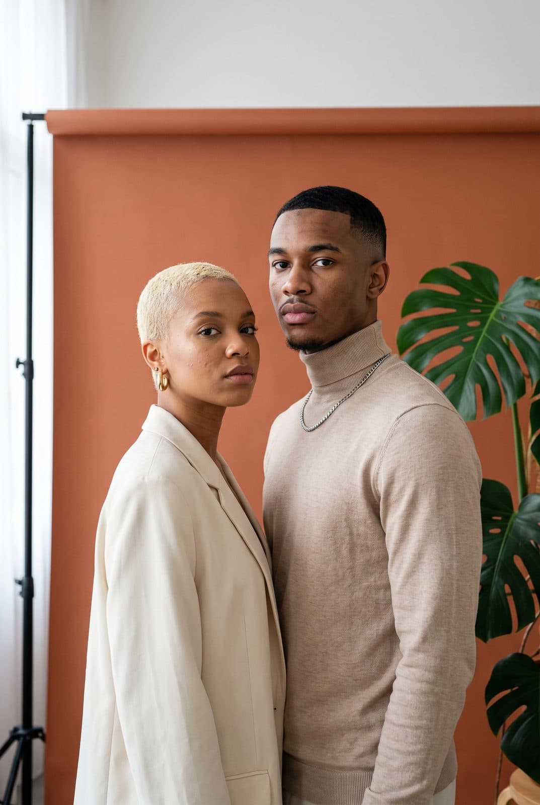 Un couple élégant devant un fond terracotta et un monstera