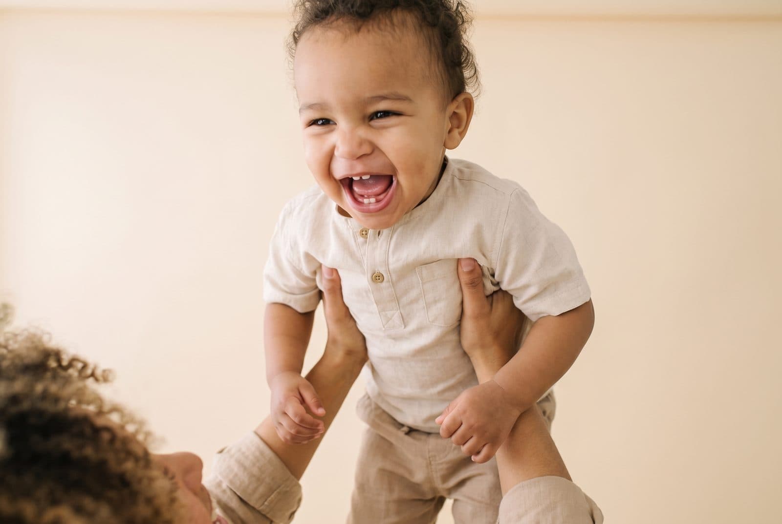 Un bébé éclate de rire, soulevé à bout de bras
