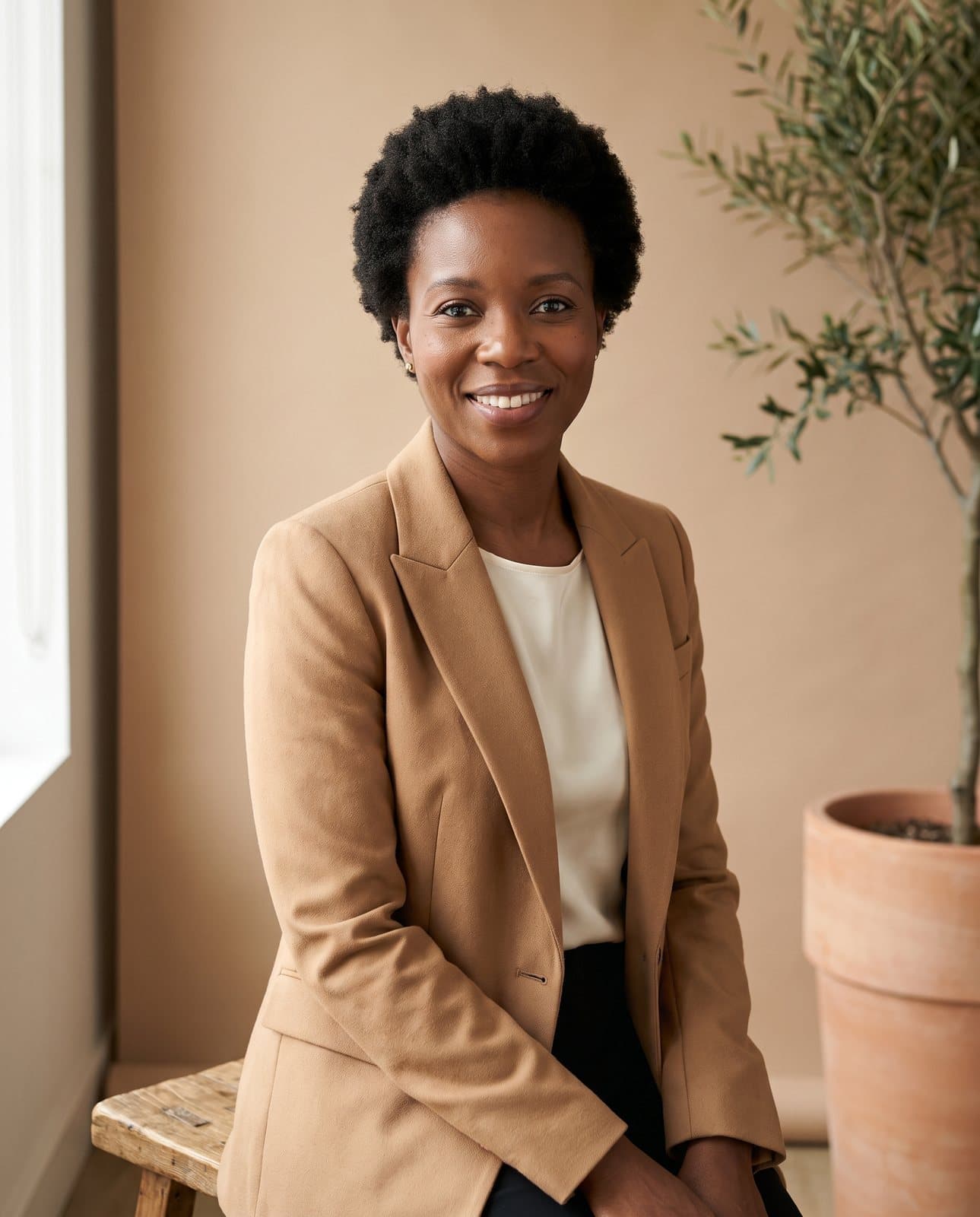 Portrait professionnel en studio : femme en blazer camel, fond neutre, regard franc